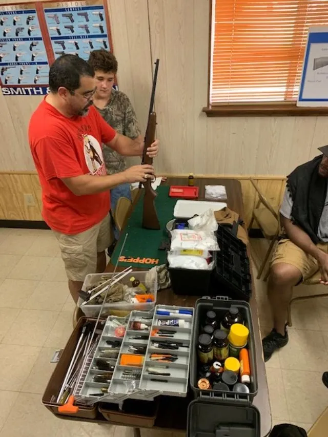 A group of people standing around a table with guns.