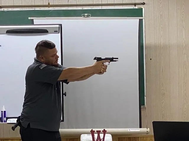A man holding a gun in front of a projector screen.