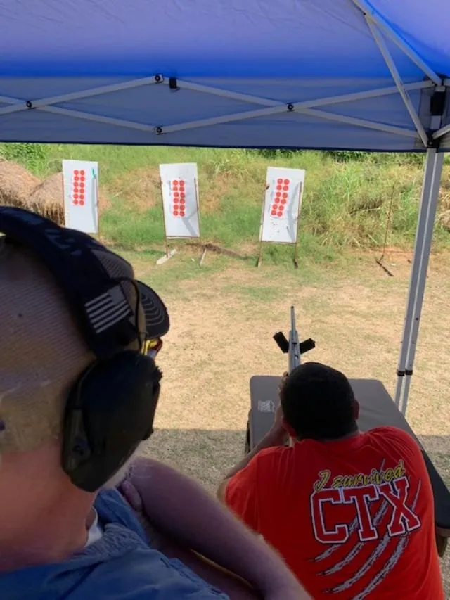 A man with ear protection and headphones is shooting at targets.