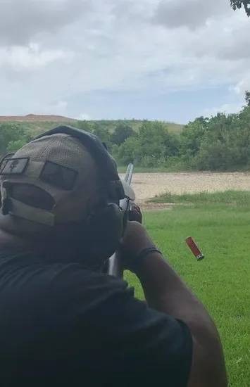 A man is holding his gun up to the side of his face.