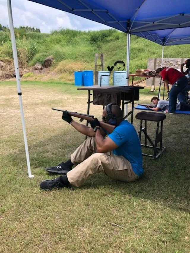 A man sitting on the ground holding a rifle.