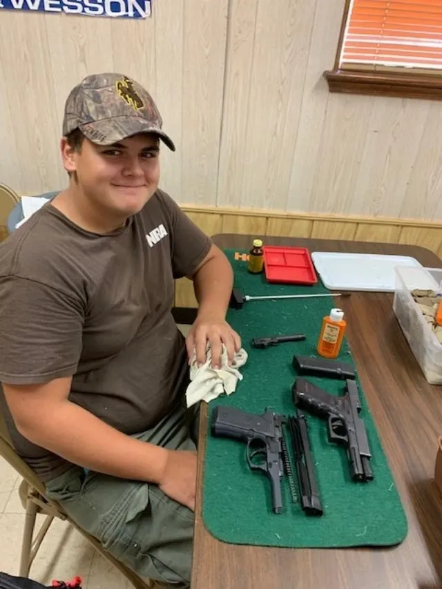 A man sitting at a table with two guns.