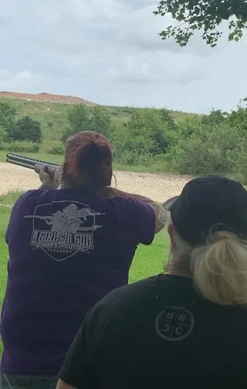 A woman is holding a gun while another person watches.