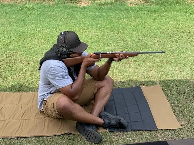 A man sitting on the ground with a rifle.