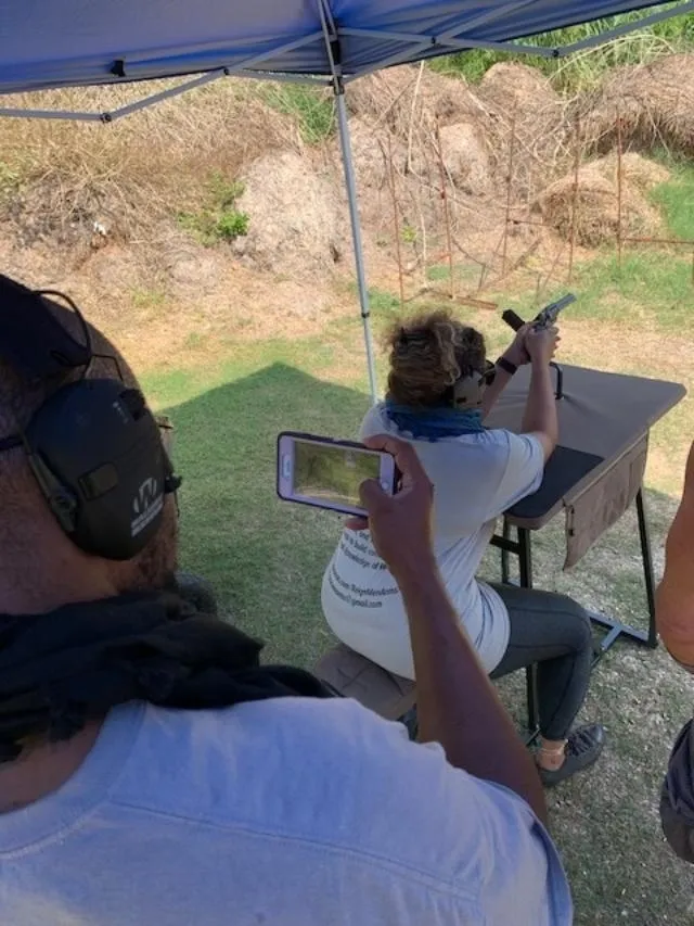 A man taking a picture of another person shooting.