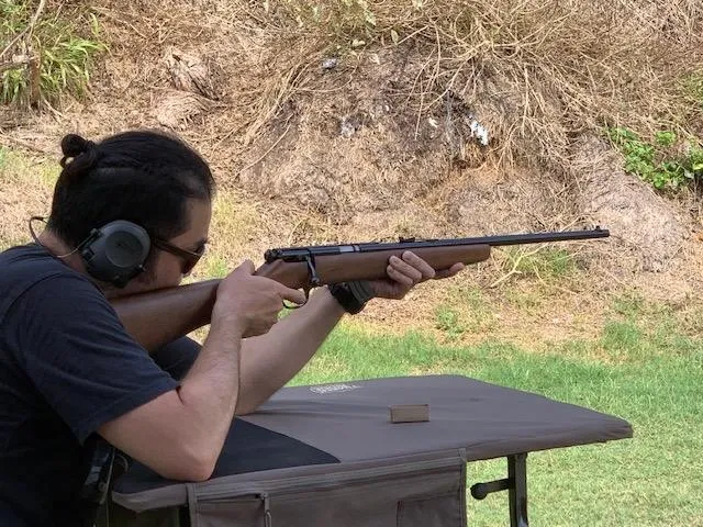 A man is holding a rifle and aiming it.