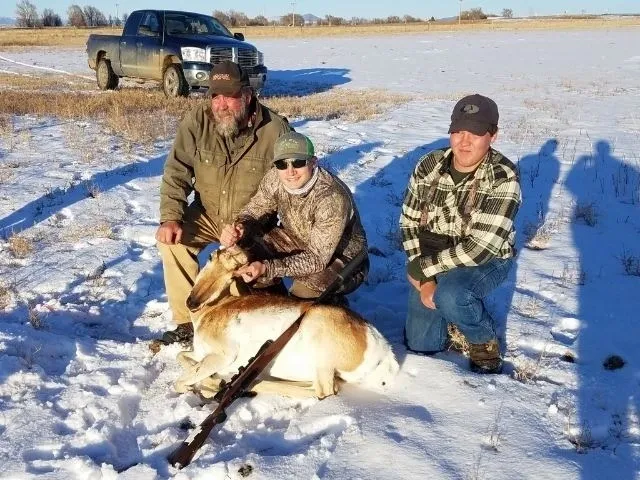 A man and two women with a dog in the snow.