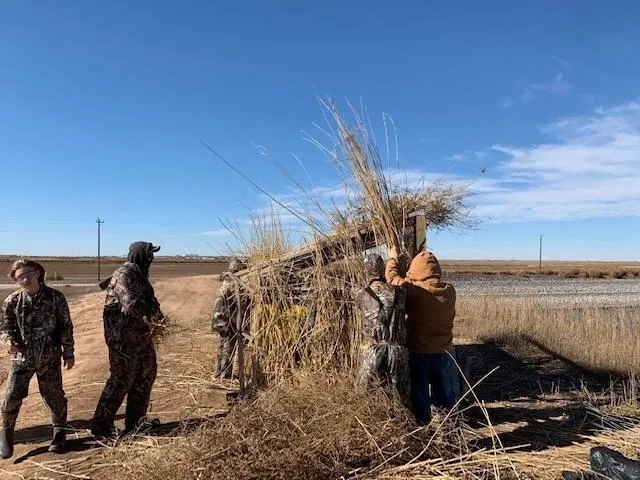 A group of people standing around in the grass.