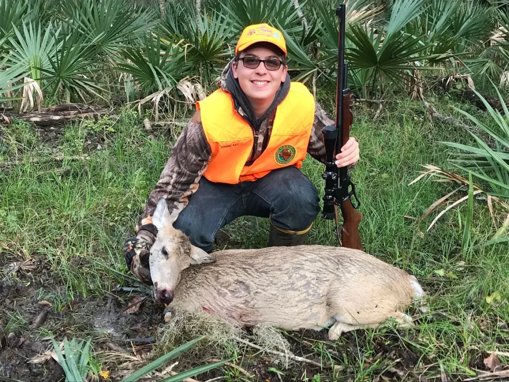 A woman kneeling down next to a dead animal.