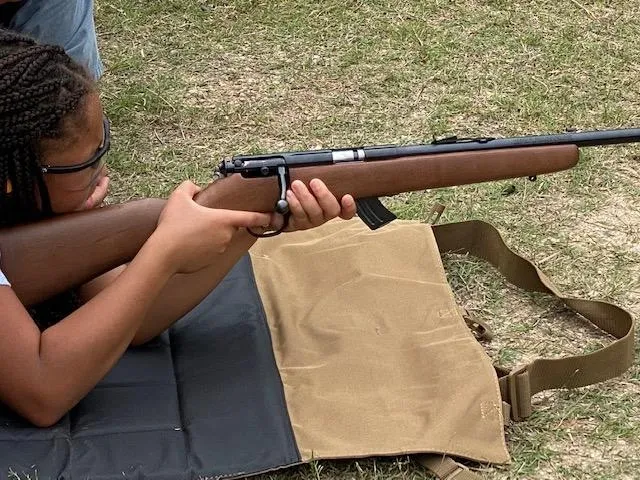 A person sitting on the ground holding a rifle.