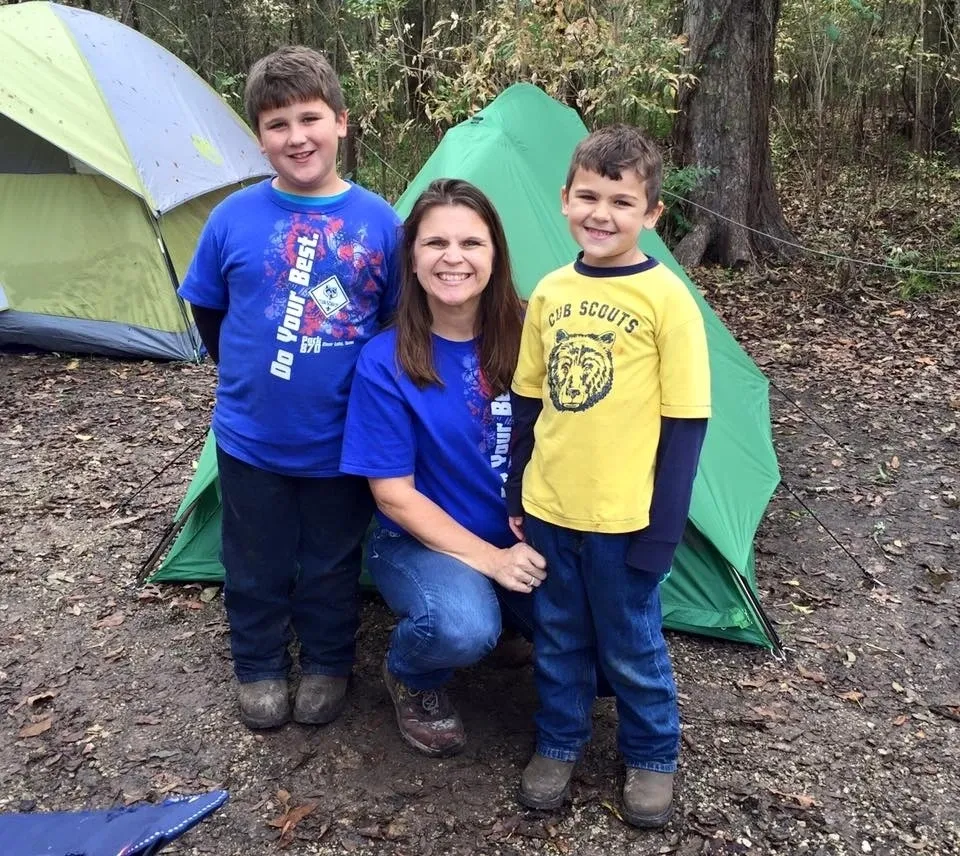 A woman and two boys standing in front of an open tent.