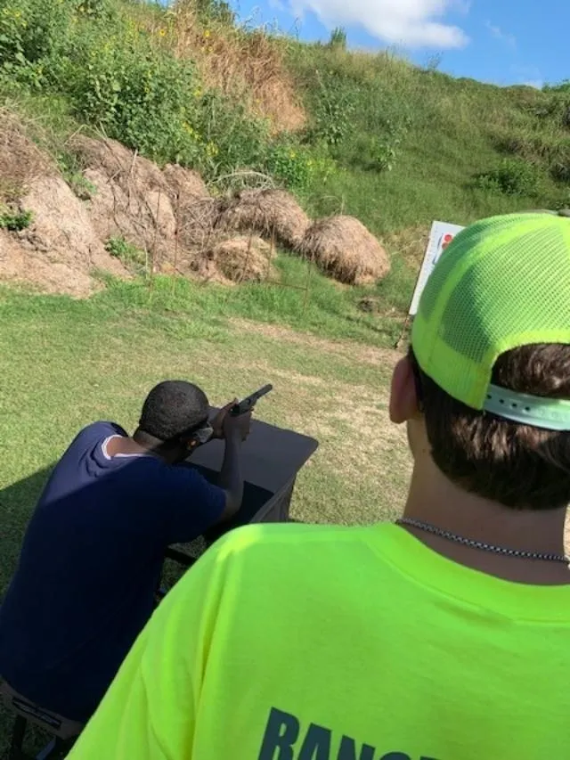 A man in yellow shirt and hat aiming at something.