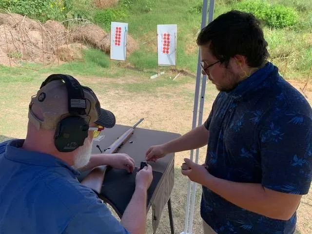 A man is holding a gun while another person holds something.