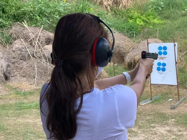 A woman wearing headphones and holding a gun
