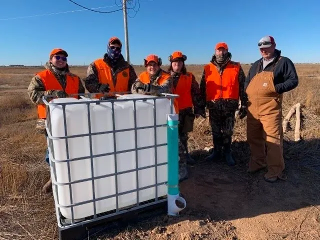 A group of people standing next to a large container.