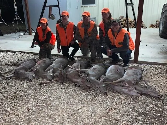 A group of people standing around dead animals.