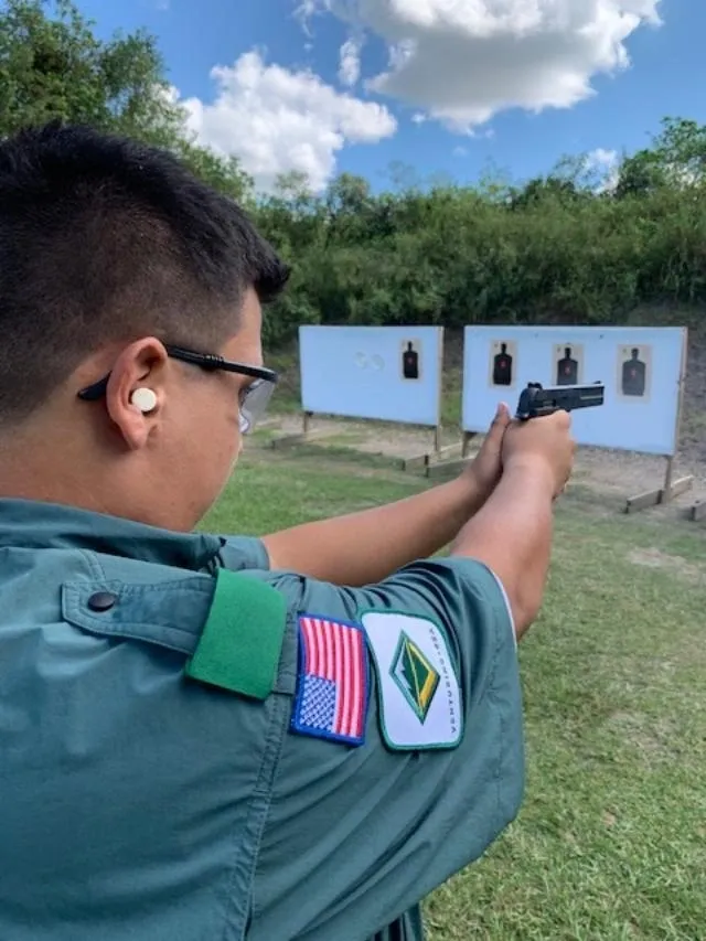 A man in uniform holding a gun at the range.