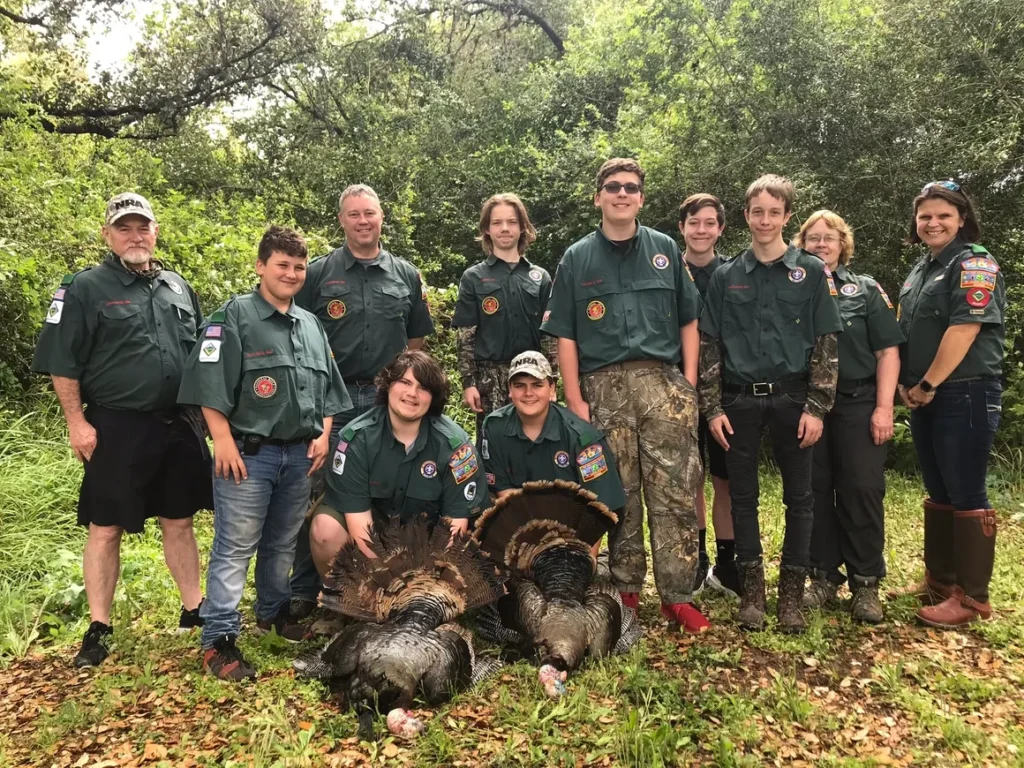 A group of people standing next to turkeys.