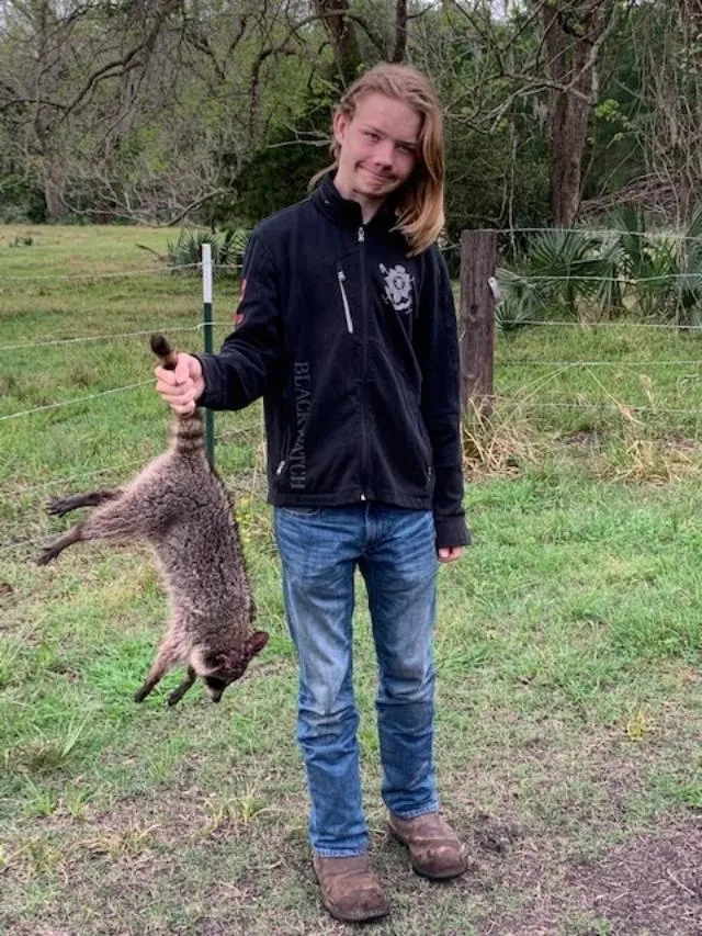 A young man holding an animal in his hand.