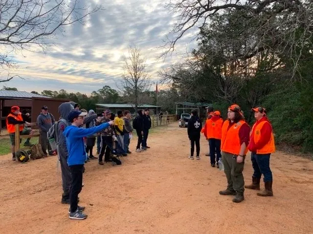 A group of people standing around in the dirt.