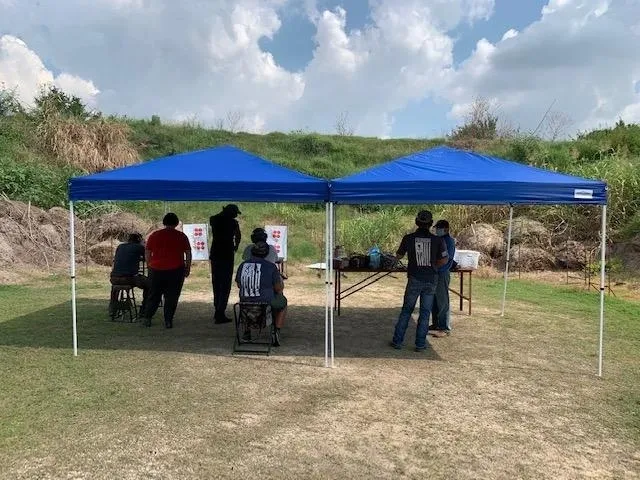 A group of people standing under a blue tent.