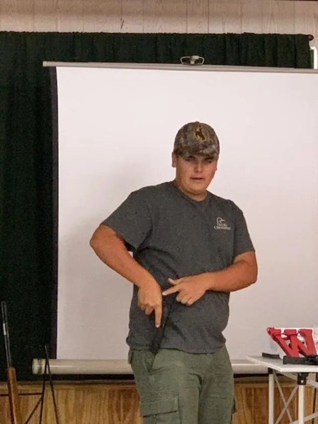 A man holding a knife in front of a white wall.