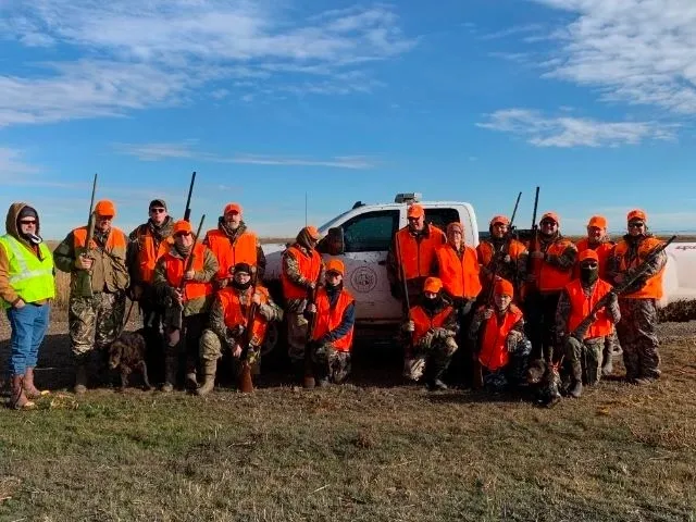 A group of people in orange jackets standing next to a truck.