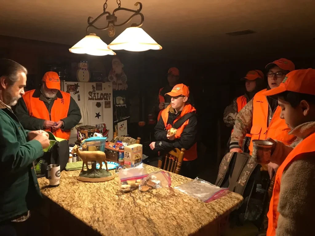 A group of people in orange vests standing around a table.