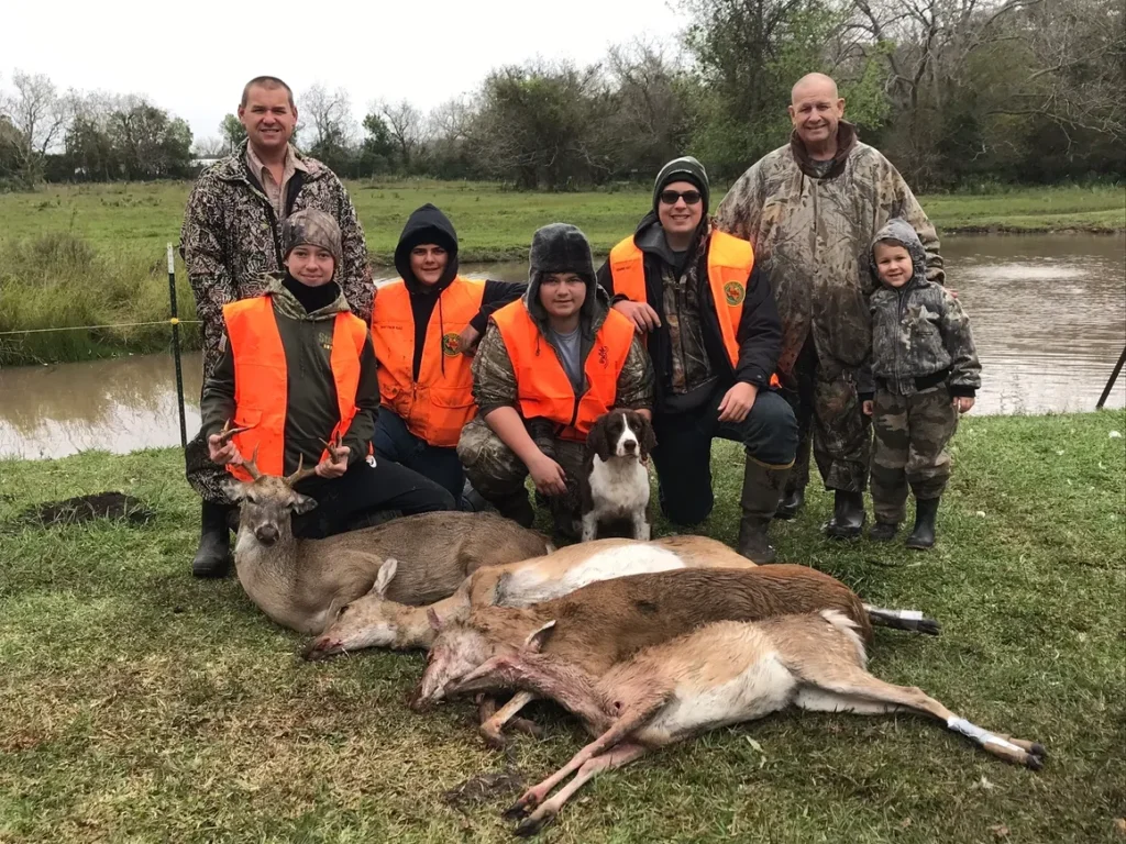 A group of people standing around dead deer.