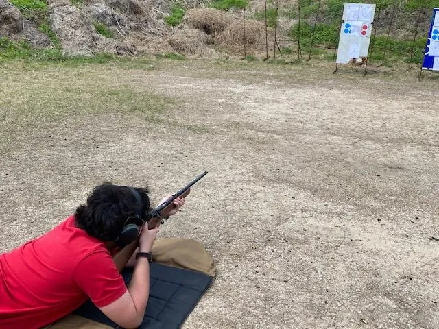A person is sitting on the ground holding a gun