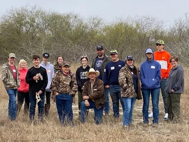 A group of people standing in the grass.