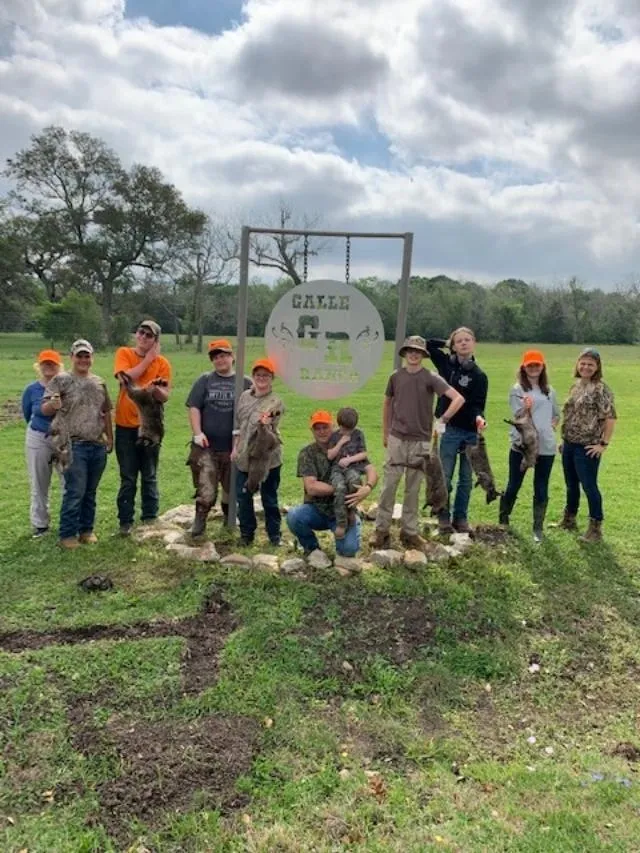 A group of people standing in the grass with guns.