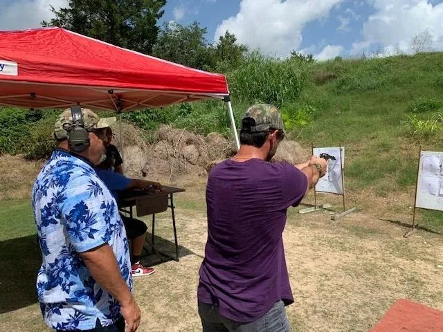 A man is shooting at an event with another man.