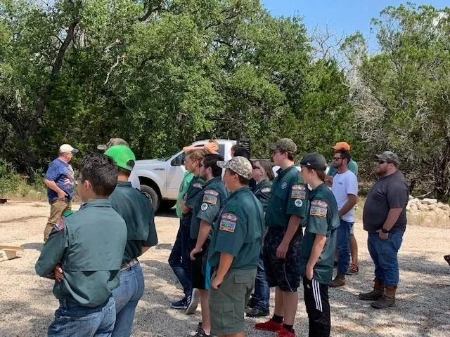 A group of people standing around in front of a truck.