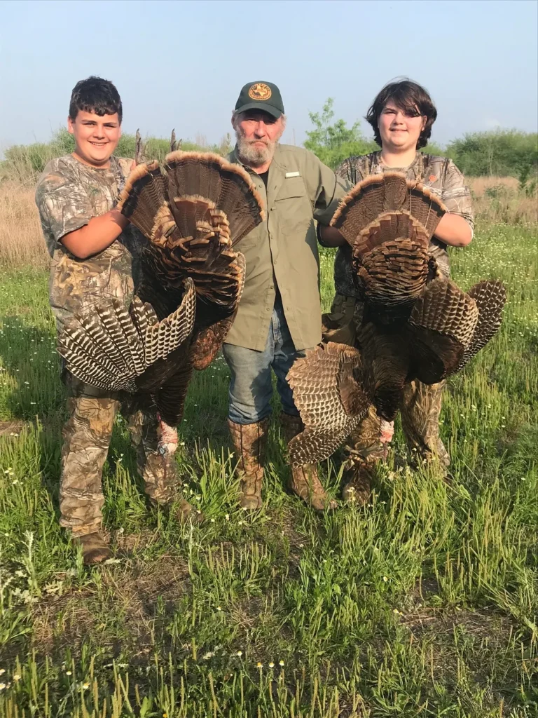 Three people holding turkeys in their hands.