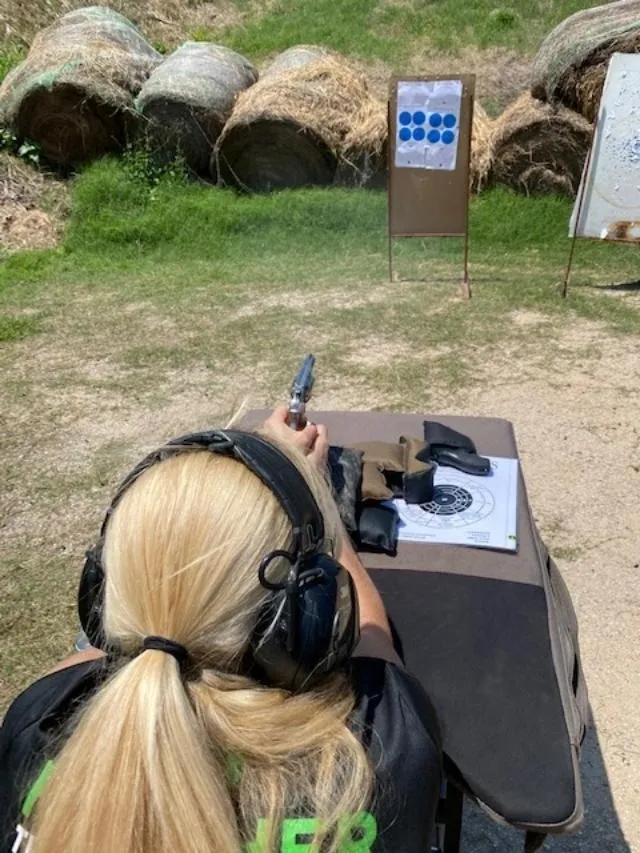 A woman is holding a gun and wearing headphones.