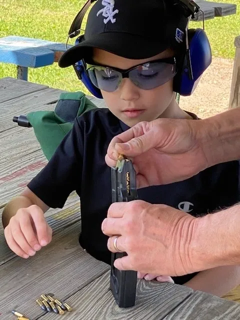 A boy wearing sunglasses and a helmet is holding something.