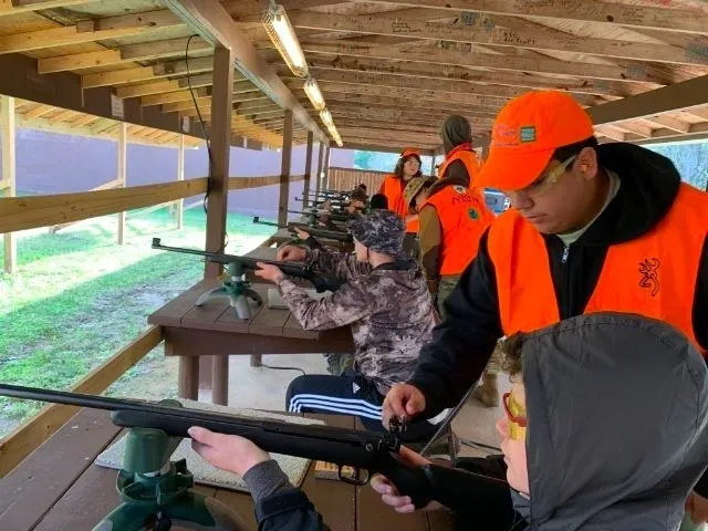 A group of people in orange vests holding guns.