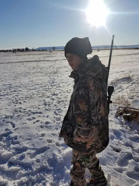 A young boy in camouflage with a rifle.