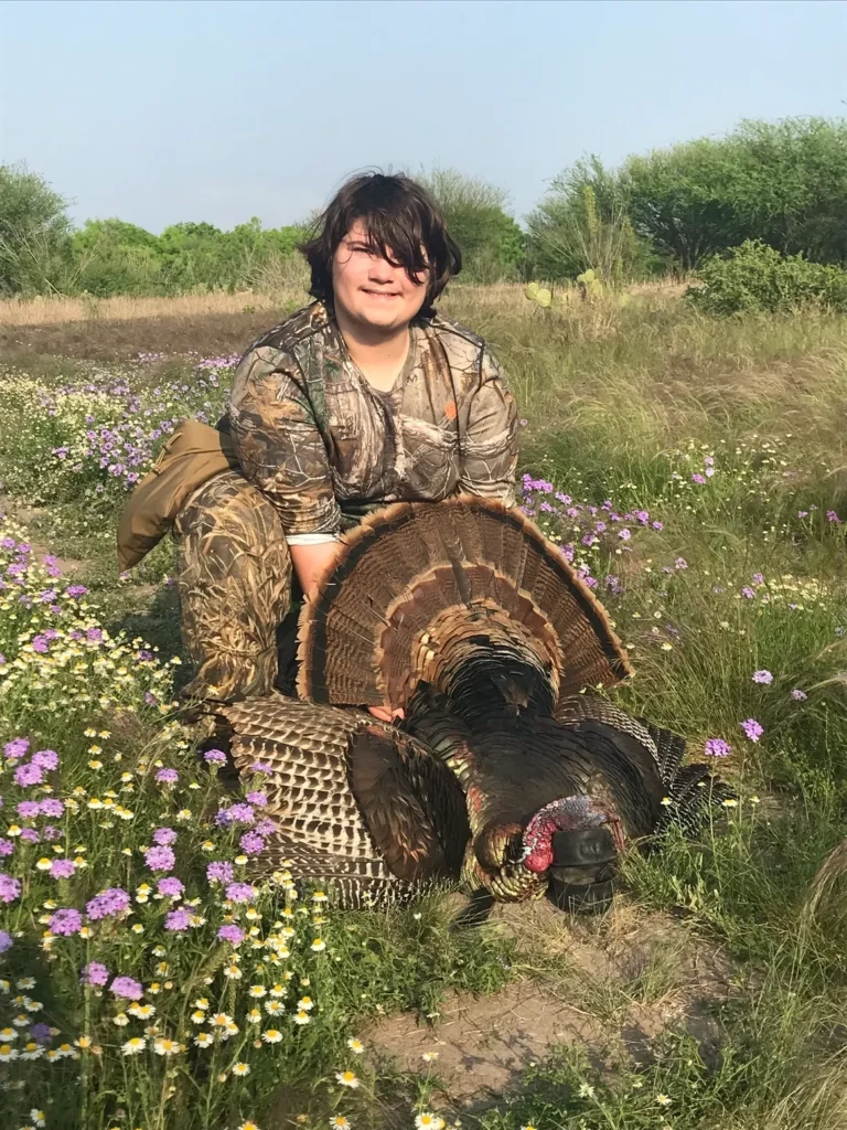 A woman sitting on the ground with two turkeys.