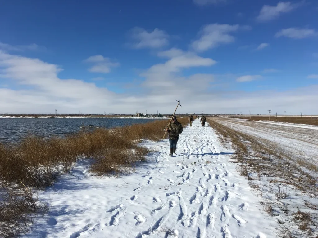 A person walking on snow covered ground near water.