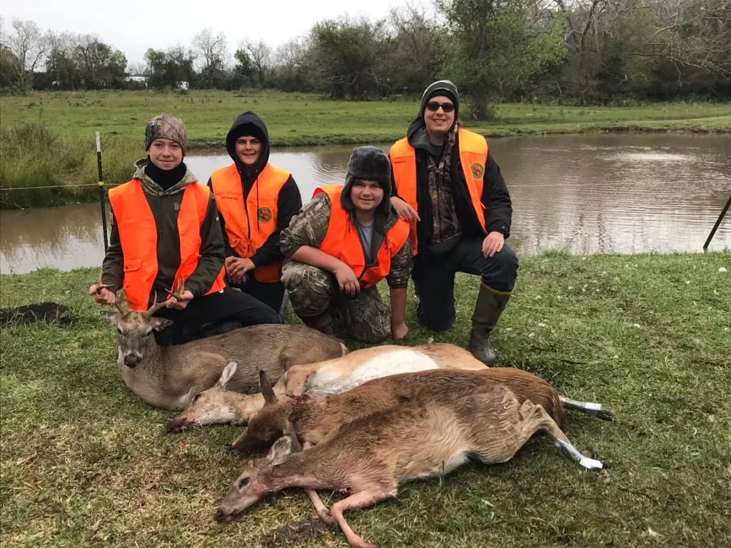 A group of people standing next to dead deer.