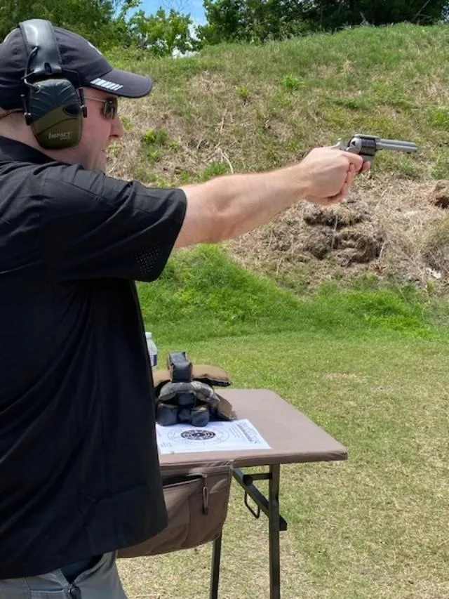 A man is holding a gun and pointing it at something.