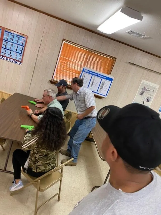 A group of people sitting at tables in front of a wall.