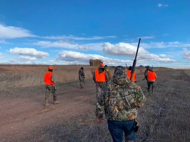 A group of people in orange vests with guns.