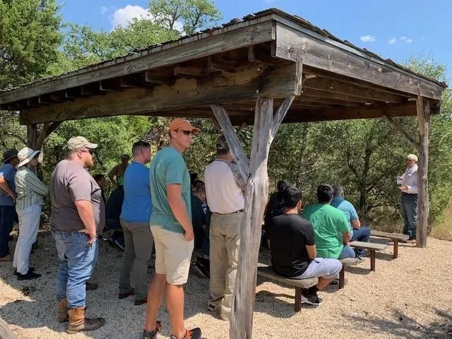 A group of people standing around under an awning.