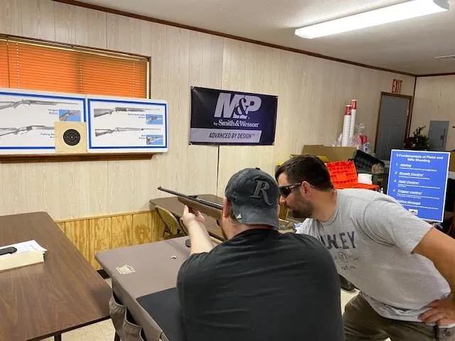 Two men are looking at a gun in the room.