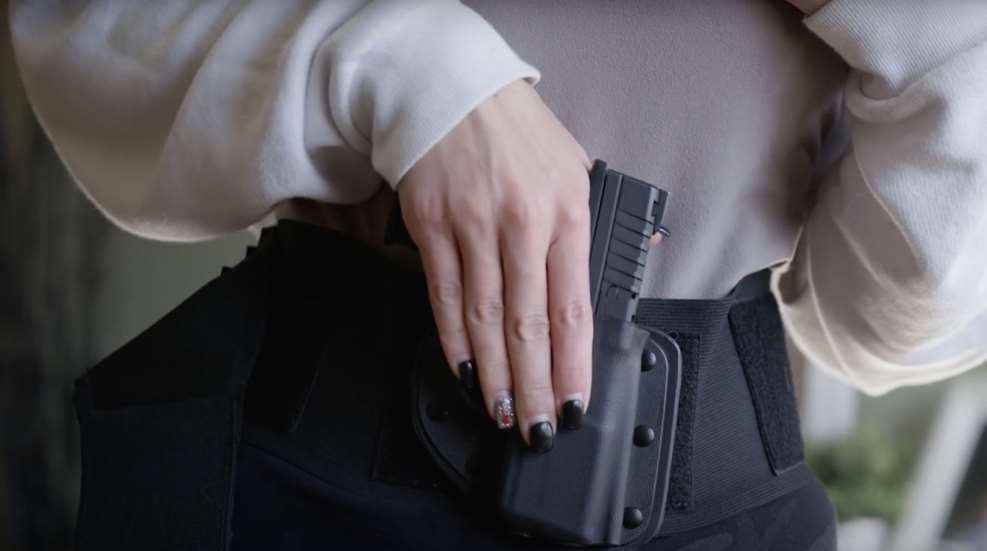 A woman 's hand is holding a gun in her pocket.