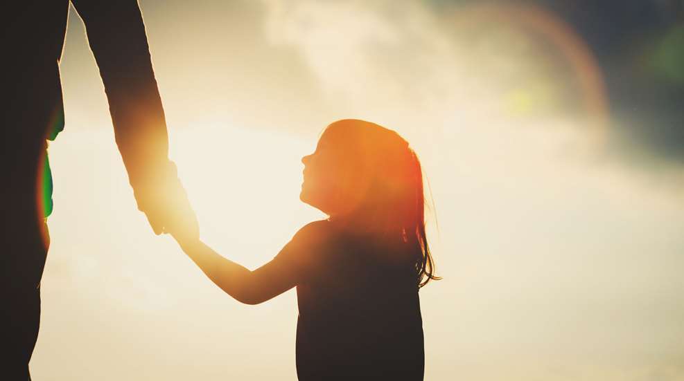 A woman holding onto the sun while standing in front of a sky.