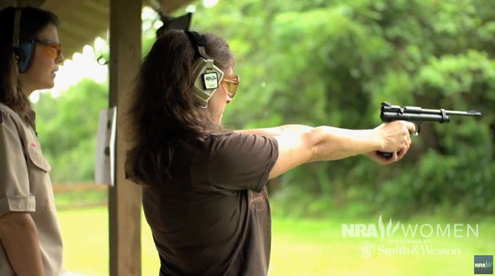 A woman is shooting at an outdoor target.